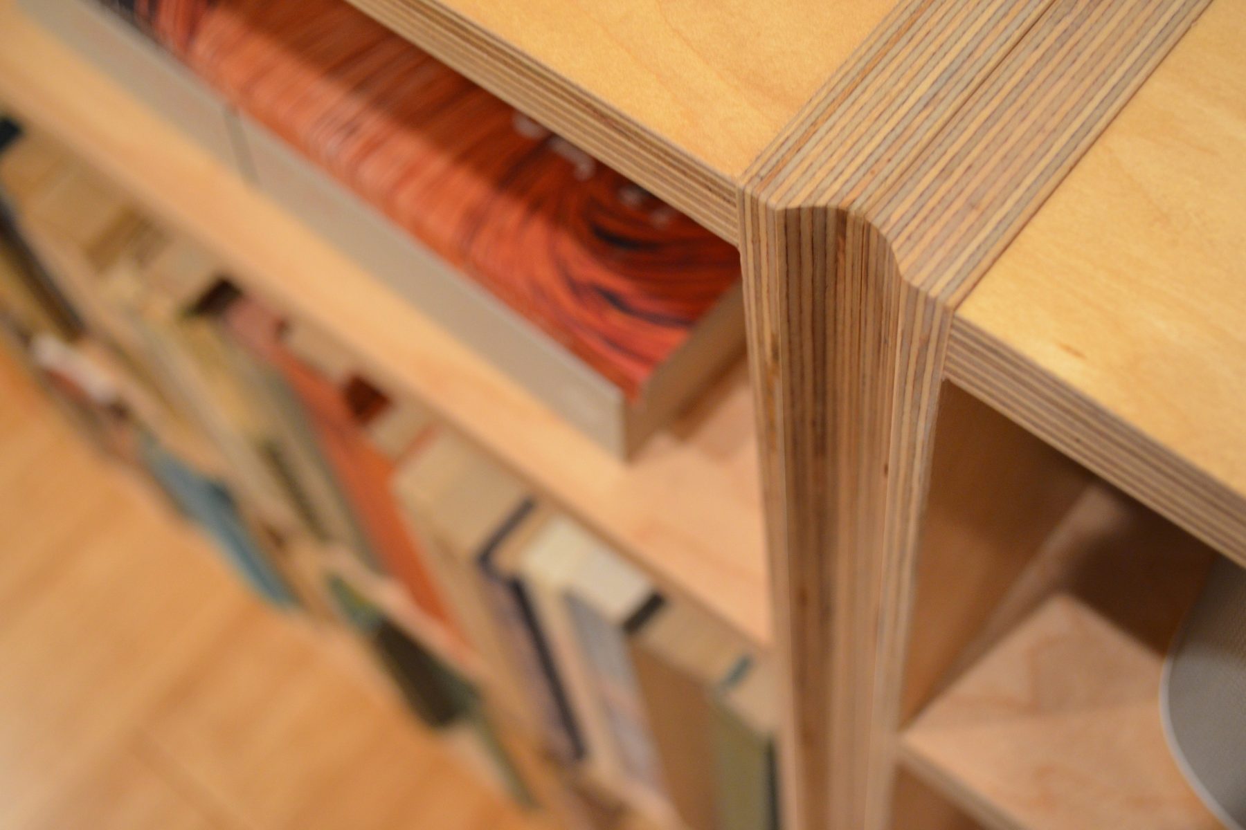 A close view of a plywood shelf joint above the fore-edges of books